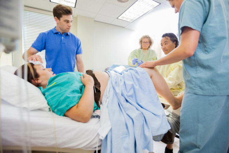 Man Looking At Doctor Delivering Baby