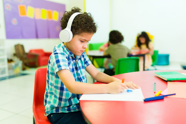 Child sits at table wearing headphones