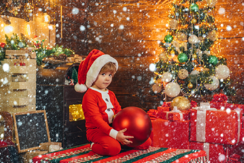 Child looks anxious while waiting in front of tree with gifts