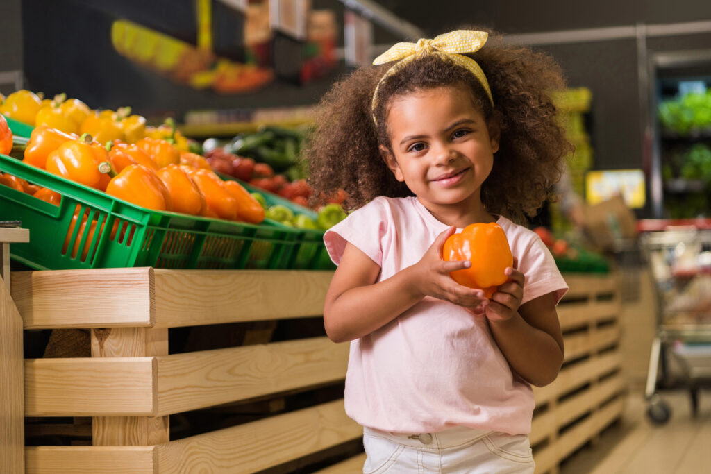 Kid picking out peppers at grocery store