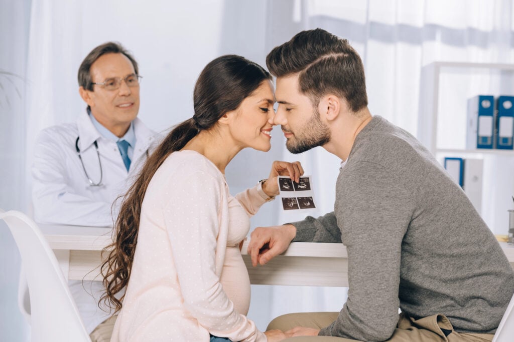 Couple celebrates pregnancy with doctor in background