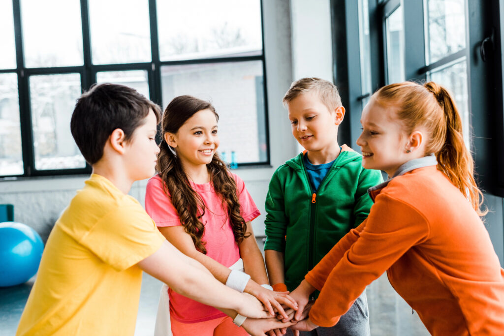 Group of happy kids holding hands in gym