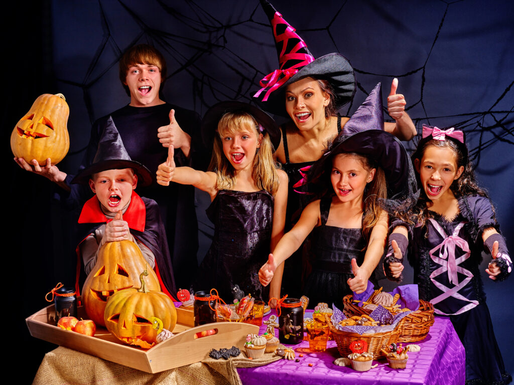 Several children in Halloween costumes have jack-o-lanterns and fun