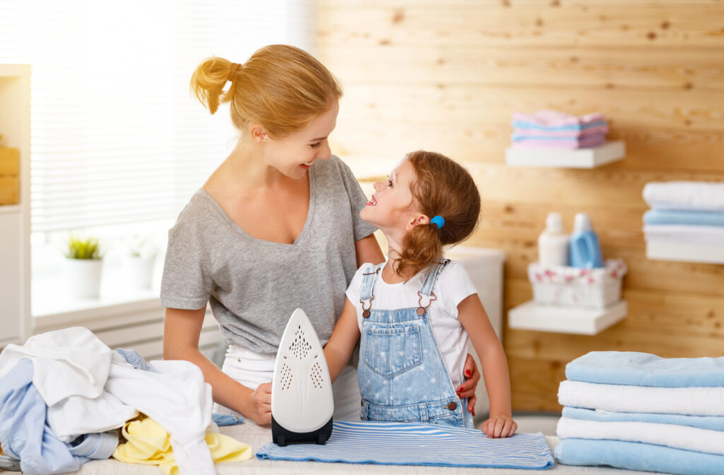 Happy family mother housewife and child daughter ironing clothes
