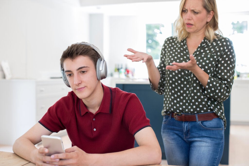 Teen ignores mom, wearing headphones and using device while she tries to talk to him