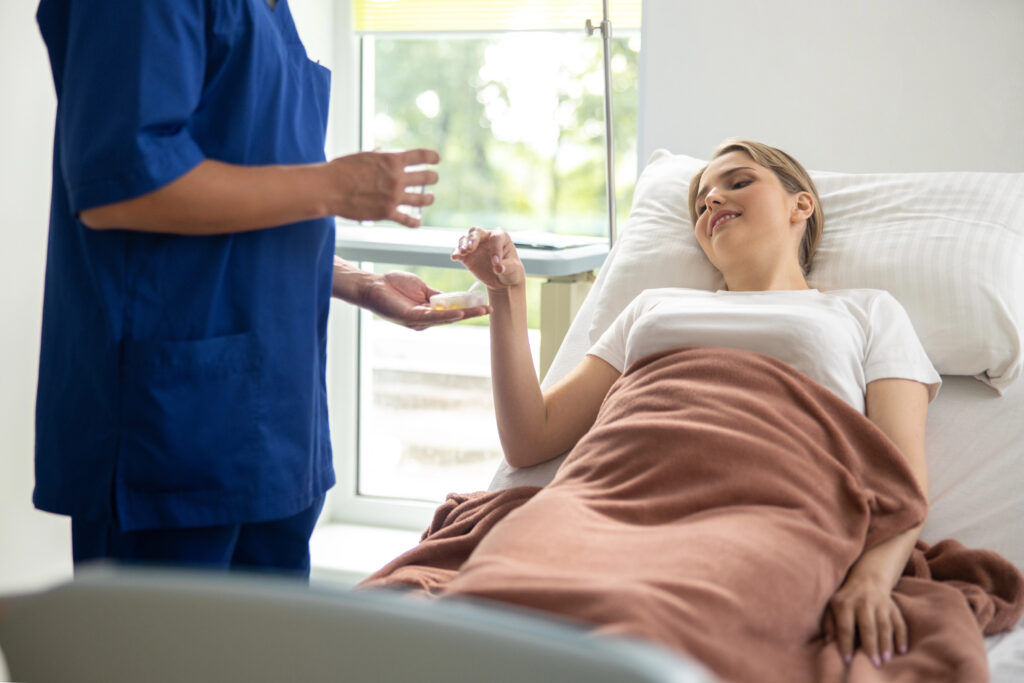 Doctor giving pills to young woman in hospital room