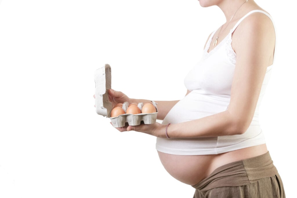 Pregnant woman holding eggs - studio shot