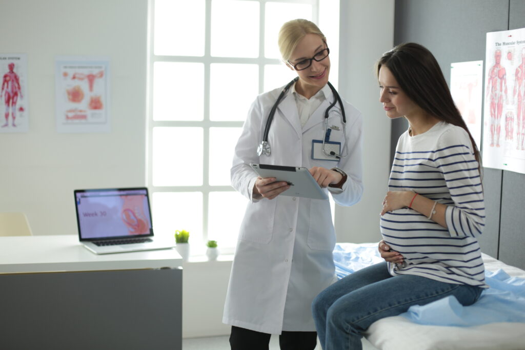 Beautiful smiling pregnant woman with the doctor at hospital